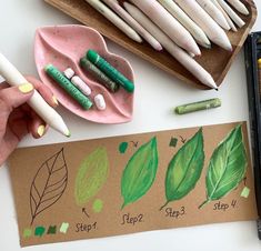 a person is holding some crayons and pencils on a table with other items