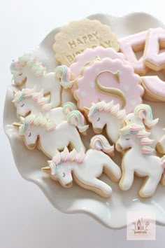 decorated cookies are arranged on a plate with the number twenty five and unicorns in pastel colors