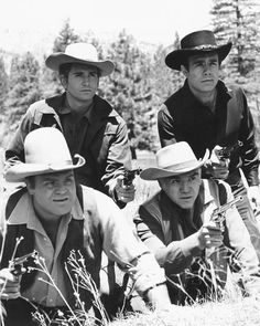 three men in cowboy hats are posing for a black and white photo with trees in the background