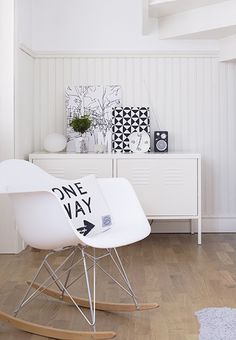 a white rocking chair sitting on top of a hard wood floor next to a dresser