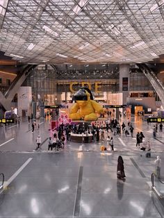 an indoor area with people walking around and large yellow object in the middle of it