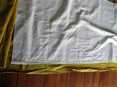 a table cloth with white lace on it sitting on a wooden floor next to a window