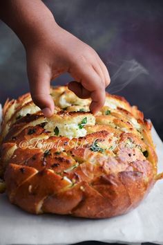 a person reaching for some food on top of a bread bun with cheese and spinach