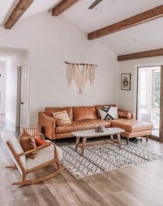 a living room filled with furniture and wooden beams on the ceiling, along with a large window