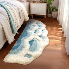 a bed room with a neatly made bed and a blue rug on the wooden floor