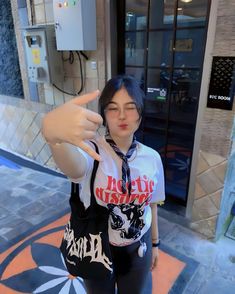 a woman standing in front of a building giving the peace sign with her right hand