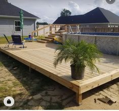 a wooden deck with a potted plant on it and a pool in the background