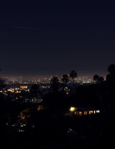 the city lights shine brightly in the dark night sky as seen from an overlook point