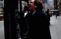 a man standing next to a parking meter on the side of a street with his mouth open