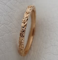 a gold wedding band that has been made to look like it is carved with leaves