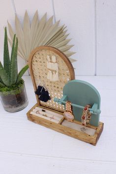 a small wooden box with jewelry in it next to a potted succulent