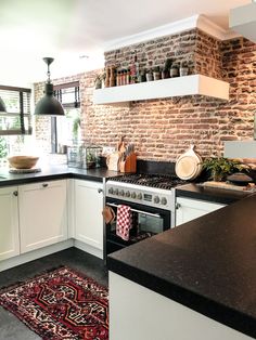 a kitchen with white cabinets and black counter tops, an area rug on the floor