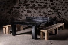 a black table and two benches in front of a brick wall