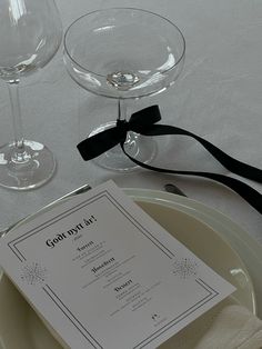 two wine glasses sitting on top of a table next to a menu and utensils