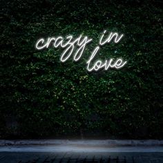 the words crazy in love are lit up against a dark background with green leaves on it