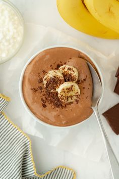 a bowl of chocolate pudding with bananas on the side