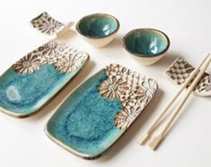 three bowls and two chopsticks are sitting on a white surface with blue glaze