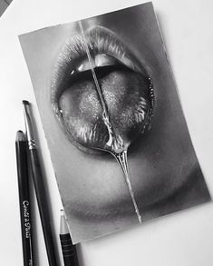 a black and white photo of a woman's mouth with two pencils next to it