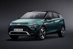 the front end of a green suv in a dark room with grey walls and flooring