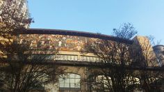 an old building with many paintings on it's side and trees in the foreground