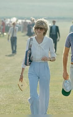 a man and woman walking in the grass with hats on their heads while others walk behind them