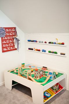 a child's play table with toy train tracks and toys on the shelf above it