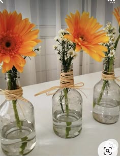 three glass vases with flowers tied to them