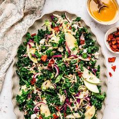 a salad in a pie pan with apples and other toppings on the table next to it