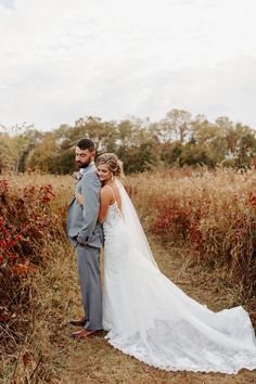 a bride and groom standing in the middle of a field