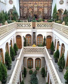 an indoor courtyard with potted plants and trees in the center, surrounded by ornate balconies