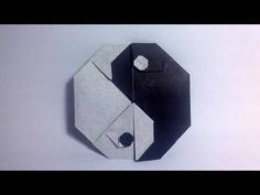 an origami clock with black and white paper on the face, in front of a gray background