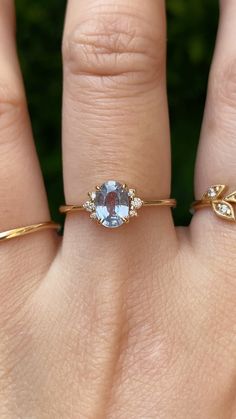 a woman's hand with two gold rings and a blue topazte ring