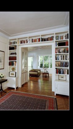 a living room filled with lots of books on top of a hard wood floor next to a doorway