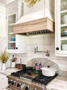 a stove top oven sitting inside of a kitchen next to white cabinets and counter tops