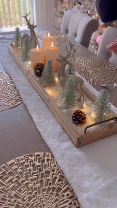 the table is set with candles, pine cones and other christmas decorations on top of it