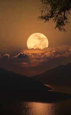 the full moon is setting over water and mountains