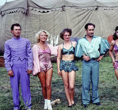 a group of people in bathing suits standing next to each other on the grass near a tent