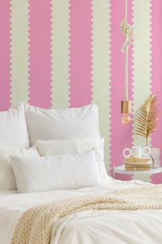 a white bed sitting next to a pink wall