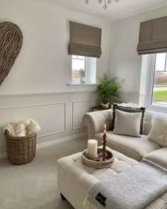 a living room filled with furniture and a candle on top of a ottoman next to a window