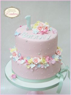 a pink cake with flowers on it and the number one frosted in icing