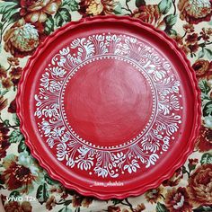 a red plate sitting on top of a floral table cloth