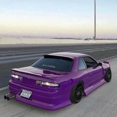 the purple car is parked on the side of the road in front of an empty highway