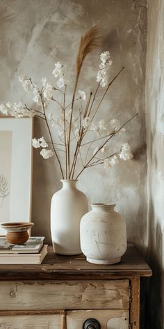 two white vases sitting on top of a wooden table next to a framed photograph