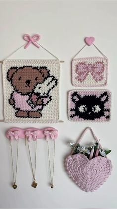 three crocheted wall hangings with teddy bears and hearts on them, one holding a baby's hand