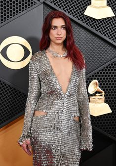 a woman with red hair wearing a silver dress at an awards event and posing for the camera