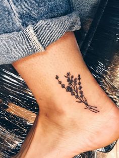 a woman's foot with a small flower tattoo on the side of her leg