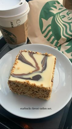 a piece of cake sitting on top of a white plate next to a cup of coffee