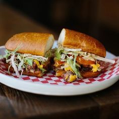 two sandwiches are sitting on a red and white checkered plate