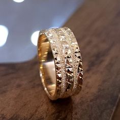 a close up of a gold ring on a wooden surface with lights in the background