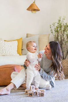 a mother and her baby playing with blocks on the floor